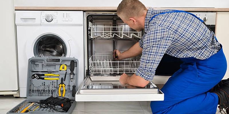 Technician with a toolbox repairing a dishwasher